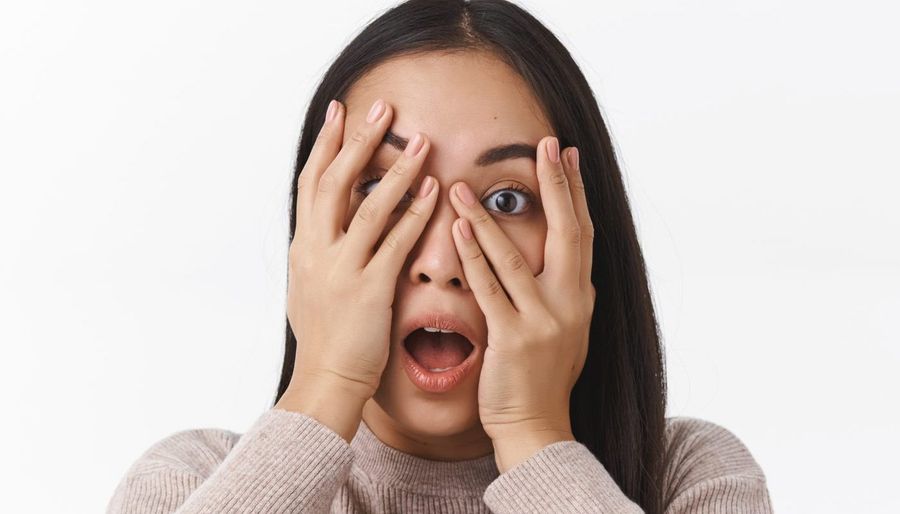 Scared embarrassed cute asian girl hiding face, hold hands above