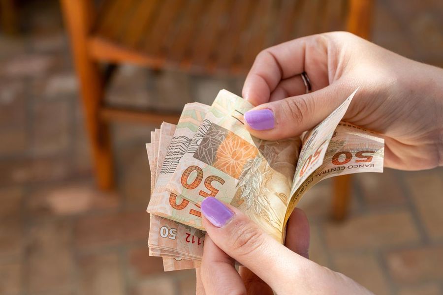 woman hand providing Brazilian money banknotes